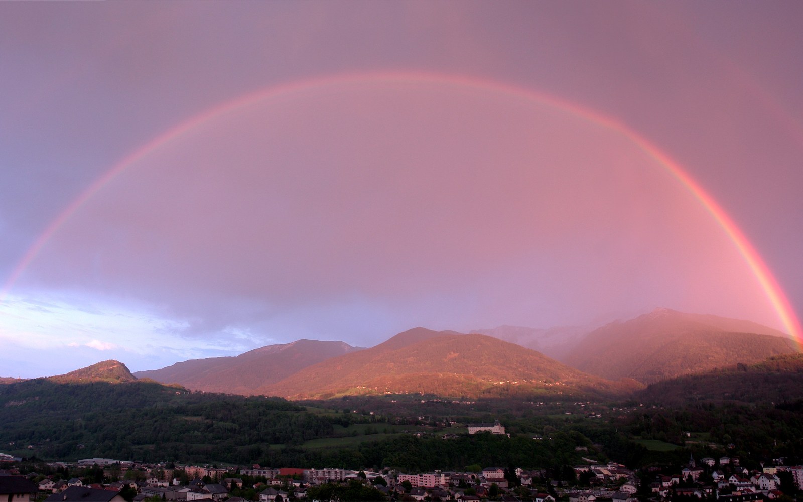 A rainbow arcing over an alpine valley town